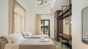 A hotel room with two beds, a desk, a chair, a mirror, and a view of the outdoors. - Tatianas Kanevaro (Chania)