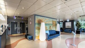 Un hall d’entrée moderne comprenant un comptoir d’accueil, un espace salon et une fresque murale.