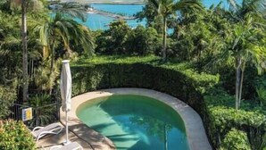 Piscina privativa cercada por vegetação exuberante e uma vista panorâmica da paisagem costeira.