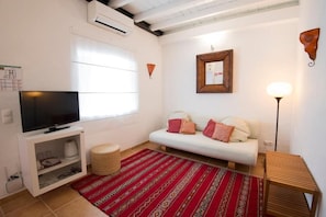 A living room with a TV, sofa, red patterned rug, and a lamp. - Monte da Corça Nova (Odemira)