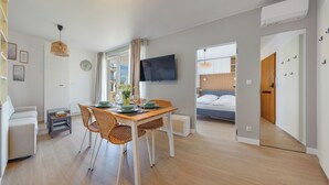 Ett modernt rum med ett matbord, stolar, en säng och en tv.