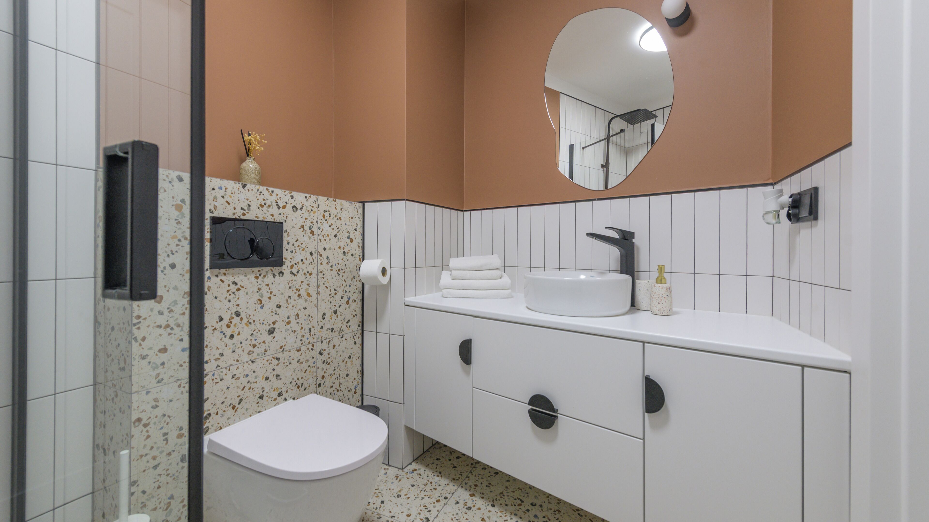 A bathroom with a white toilet, a sink with a mirror above it, and a towel rack.