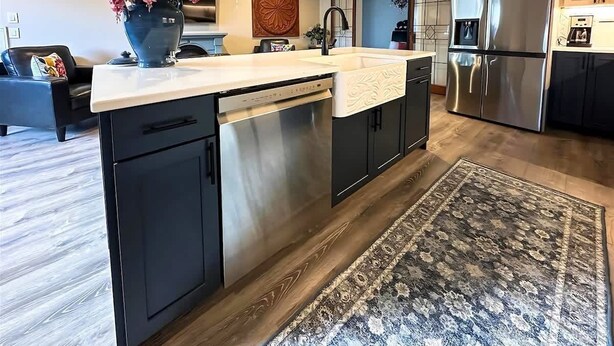 A modern kitchen with a central island, stainless steel appliances, and a patterned rug.