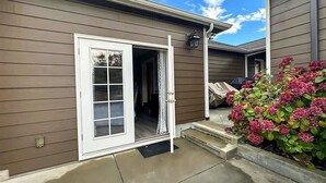 A house with a white door, a concrete porch, and a flower bed with pink flowers.