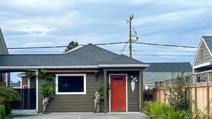 A residential house with a red door, a garage, and a front yard with plants.