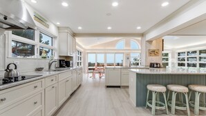 A spacious kitchen with a large island, white cabinetry, and a view of the outdoors. - Oceanfront property with a private pool! (REHOBOTH BEACH)