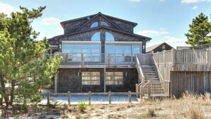A two-story house with a balcony, a staircase, and a wooden deck. - Oceanfront property with a private pool! (REHOBOTH BEACH)