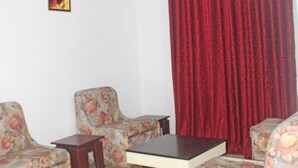 A living room with floral-patterned sofas, a small wooden table, and a red curtain.