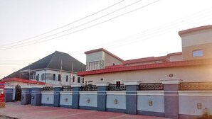 A gated building with a red roof and a signboard.