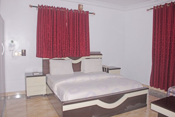 A bedroom with a bed, nightstands, and a bedside table. - Pacific Paradise Suites (Uyo)