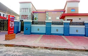 A gated entrance with a signboard listing amenities like a restaurant, bar, and pool. - Pacific Paradise Suites (Uyo)
