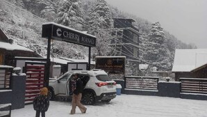 Ett snötäckt landskap med en skylt för hotellet ”Cherry Manali”.