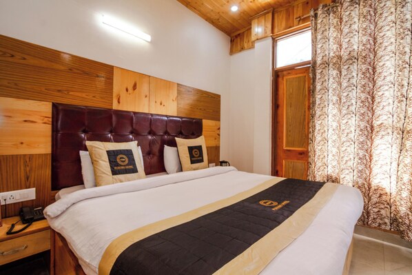 A hotel room with a wooden headboard, a bed with a black and gold bedspread, and a telephone on the nightstand. - Hotel Cherry Manali (Manali)