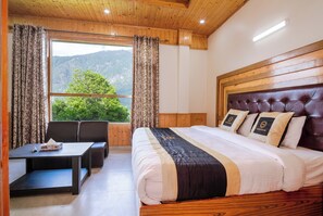 Un dormitorio con una cama grande, cabecera de madera y vistas a montañas a través de una ventana.