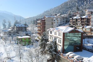 Un pueblo cubierto de nieve en la montaña con edificios de varios pisos, incluyendo un edificio destacado con fachada de vidrio.