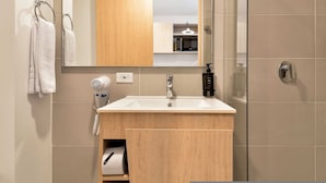 Une salle de bain moderne équipée d’un lavabo, d’un miroir, d’un porte-serviettes et d’un sèche-cheveux.