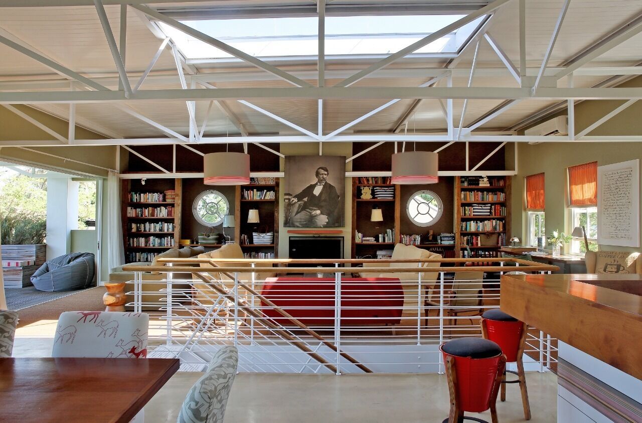 A modern library with bookshelves, a central portrait, and a staircase.