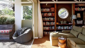 A cozy reading nook with a large bookshelf, a comfortable sofa, and a bean bag chair. - The Library (Franschhoek)