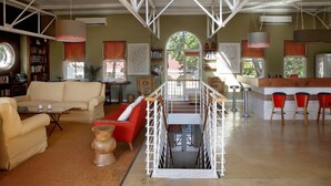 A spacious living area with a high ceiling, a staircase, and a kitchen area with bar stools. - The Library (Franschhoek)