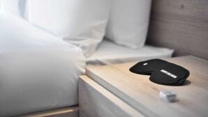 A black pillow with the text "ALWAYS DREAMING" on a wooden bedside table next to a white pillow.