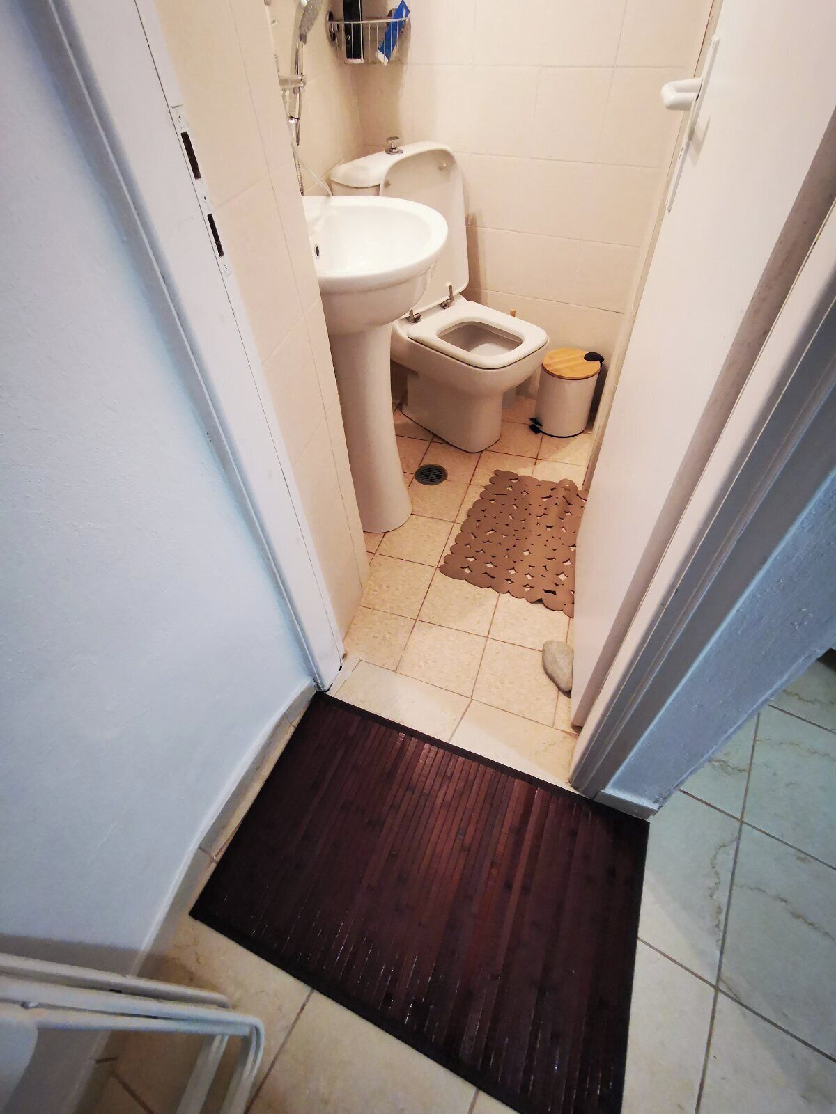 A small bathroom with a toilet, sink, and a shower area.