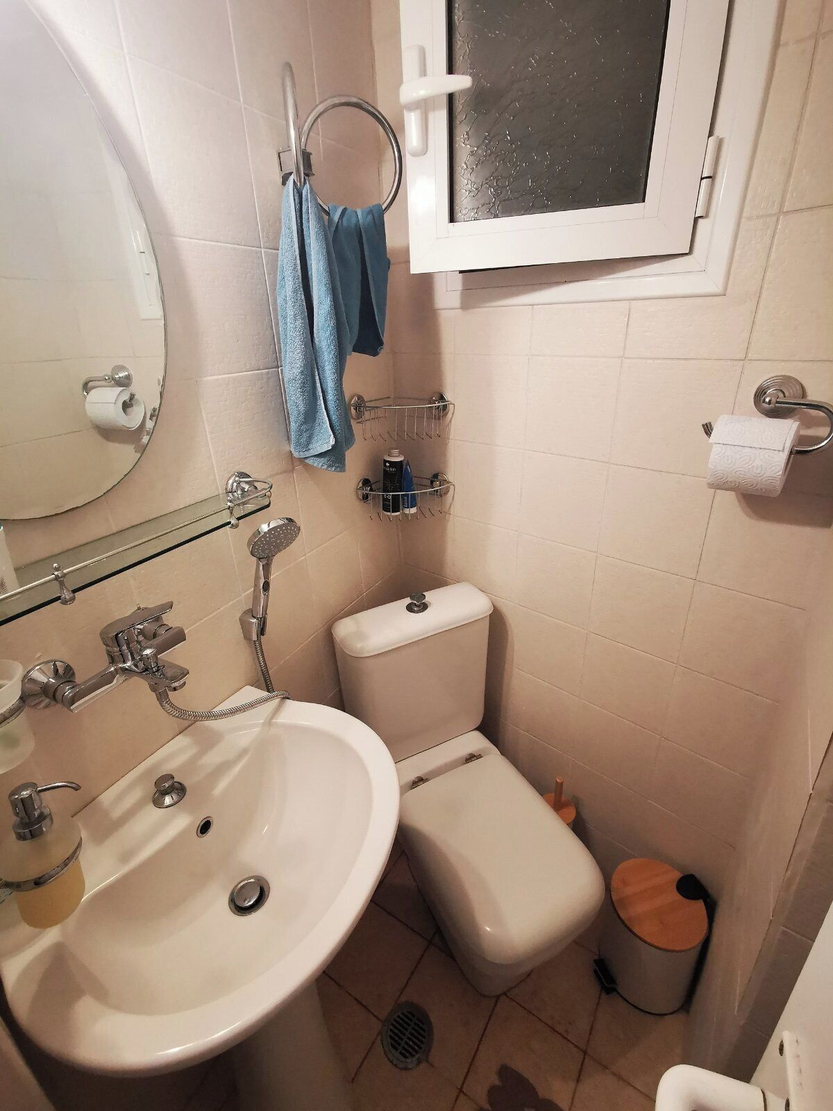 Un baño pequeño con lavamanos, inodoro y ventana sobre el inodoro.