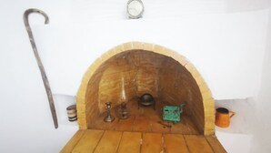 A rustic room with a wooden bench, a hanging lamp, and a small shelf with various items. - Authentic White House in Paros Lefkes (Paros)