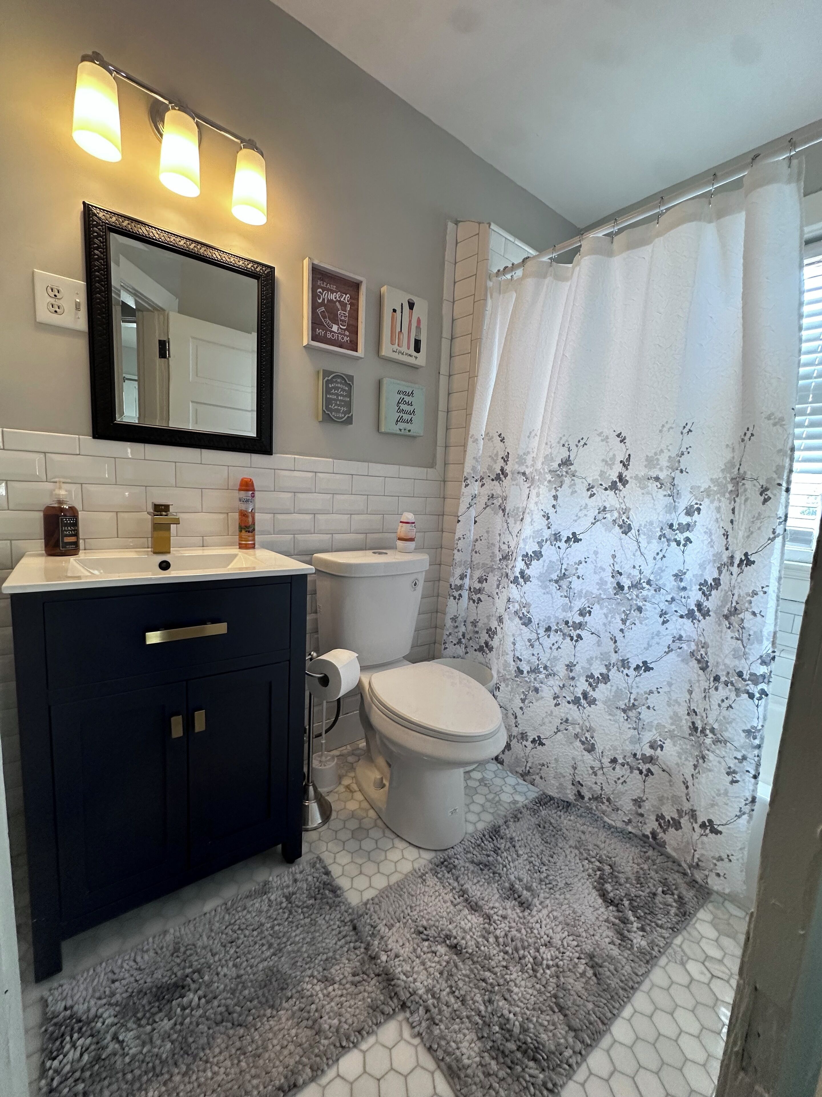 A bathroom with a dark vanity, white toilet, and shower curtain with floral pattern.