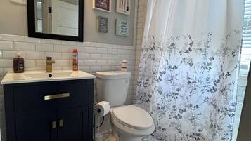 A bathroom with a dark vanity, white toilet, and shower curtain with floral pattern.