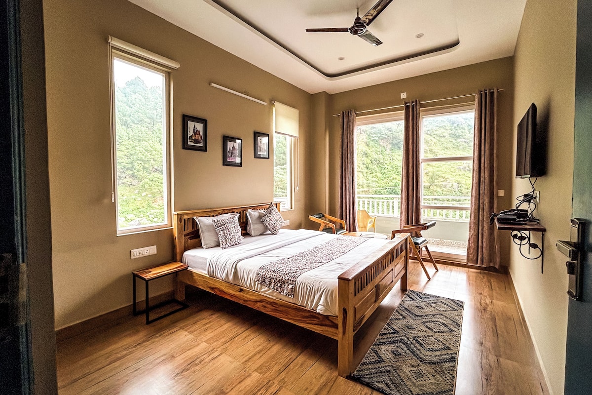 A spacious bedroom with a wooden bed, large windows, a ceiling fan, and a view of the outdoors.