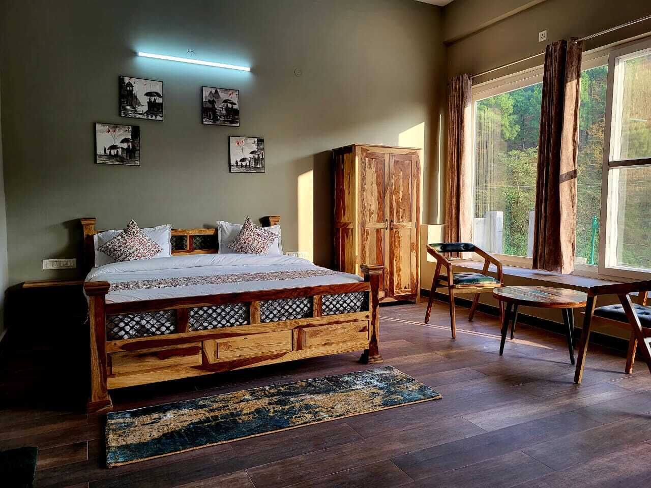 A bedroom with a wooden bed, a wooden wardrobe, a wooden bench, and a large window with curtains.