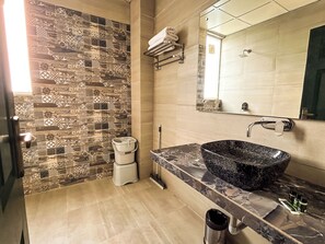 A bathroom with patterned tile walls, a sink with a black basin, and a mirror above the sink. - Hotel Alchemy Bistro & Inn (Dharamshala)