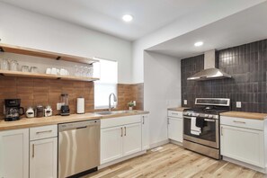 Una cocina moderna con armarios blancos, estufa de acero inoxidable y encimera de madera.