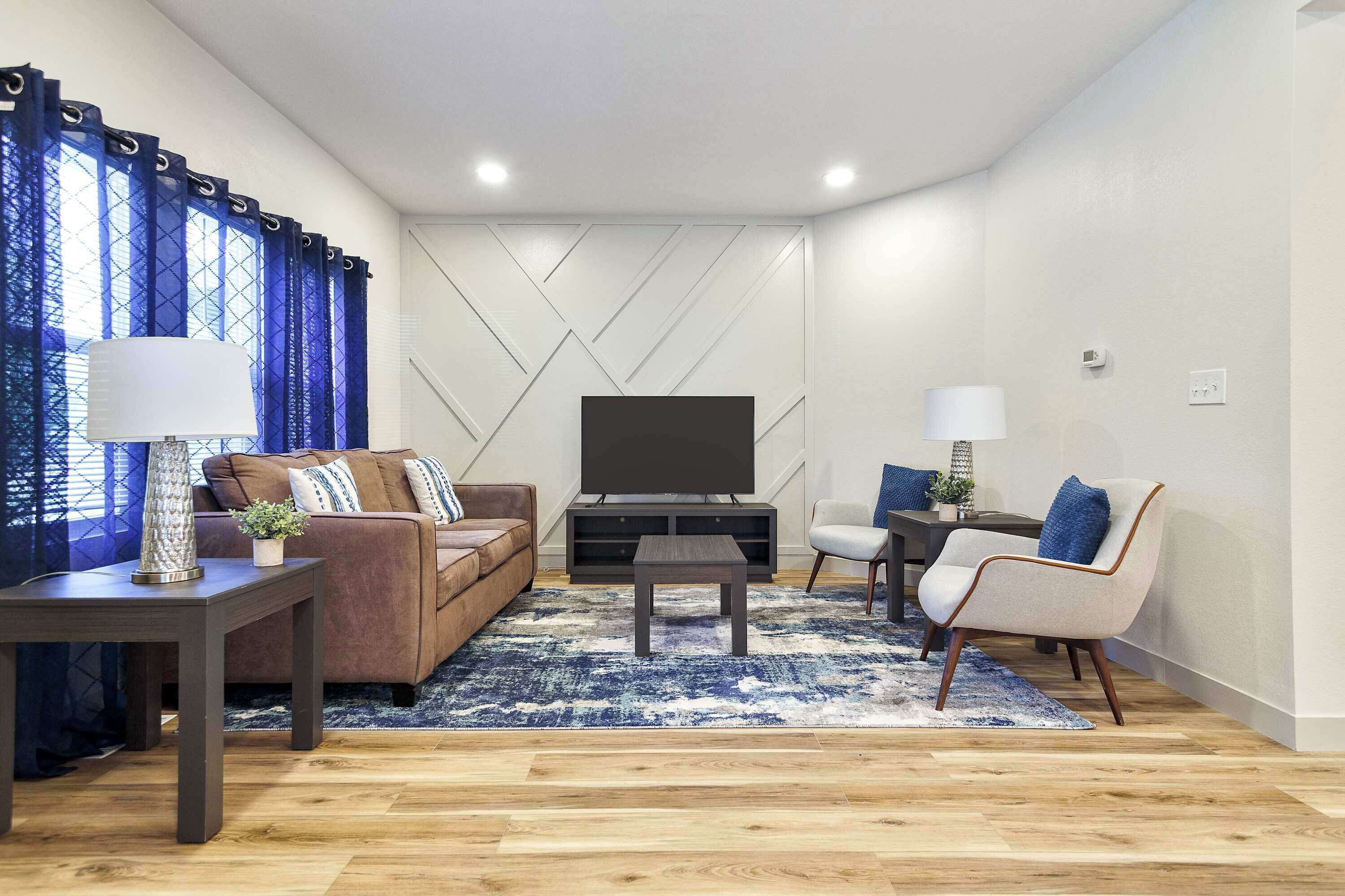 Una sala moderna con sofá, sillón, mesa de centro y mueble para televisión.