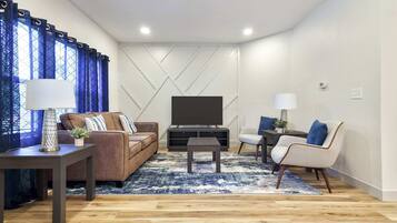 Una sala moderna con sofá, sillón, mesa de centro y mueble para televisión.