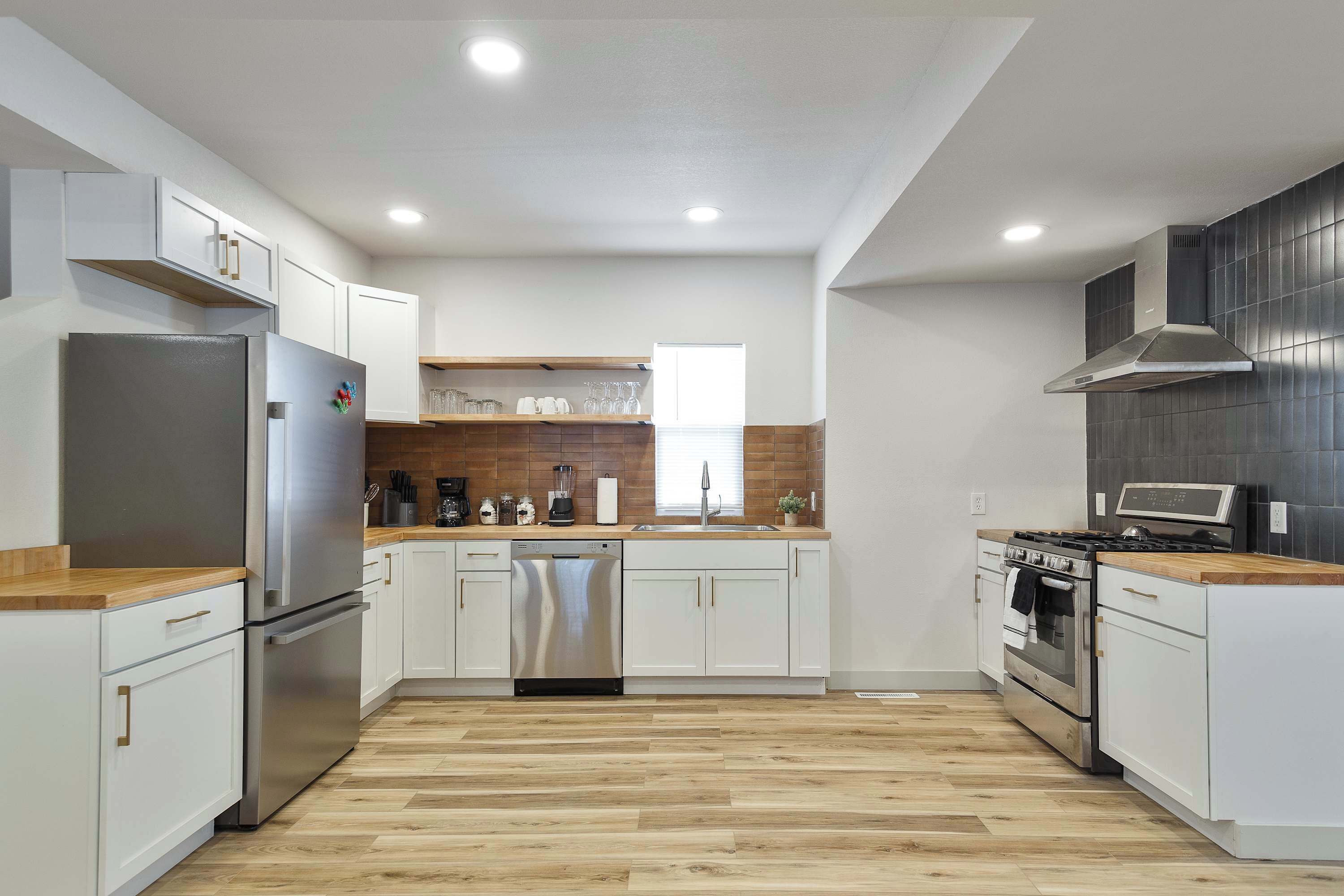 A modern kitchen with white cabinets, stainless steel appliances, and a wooden countertop.