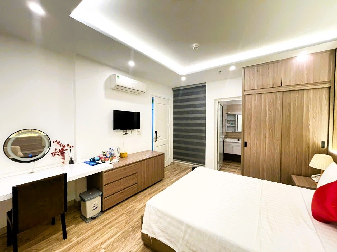 A modern bedroom with a bed, a desk, a TV, and a wardrobe.