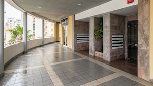 A corridor with tiled flooring, a reception area with a sign, and a wall-mounted directory.