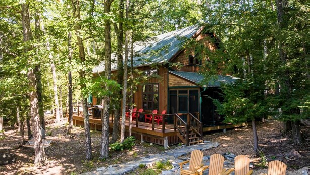 A cabin with a deck, outdoor seating, and a stone pathway.