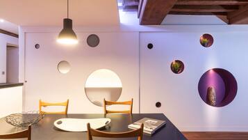 Un comedor moderno con una mesa oscura, sillas de madera y un aplique de techo.