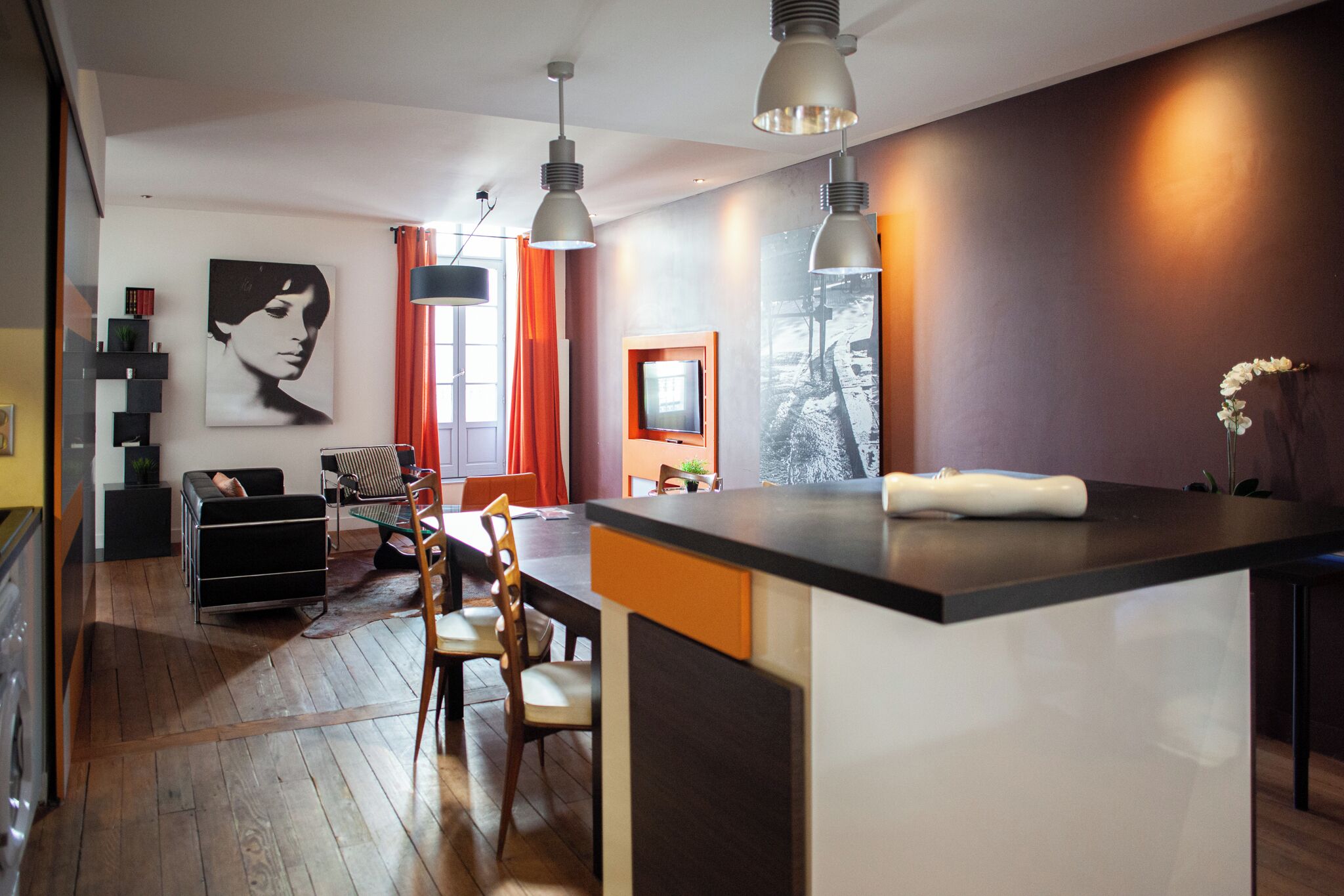 Una cocina moderna con una isla central, suelo de madera e iluminación colgante.