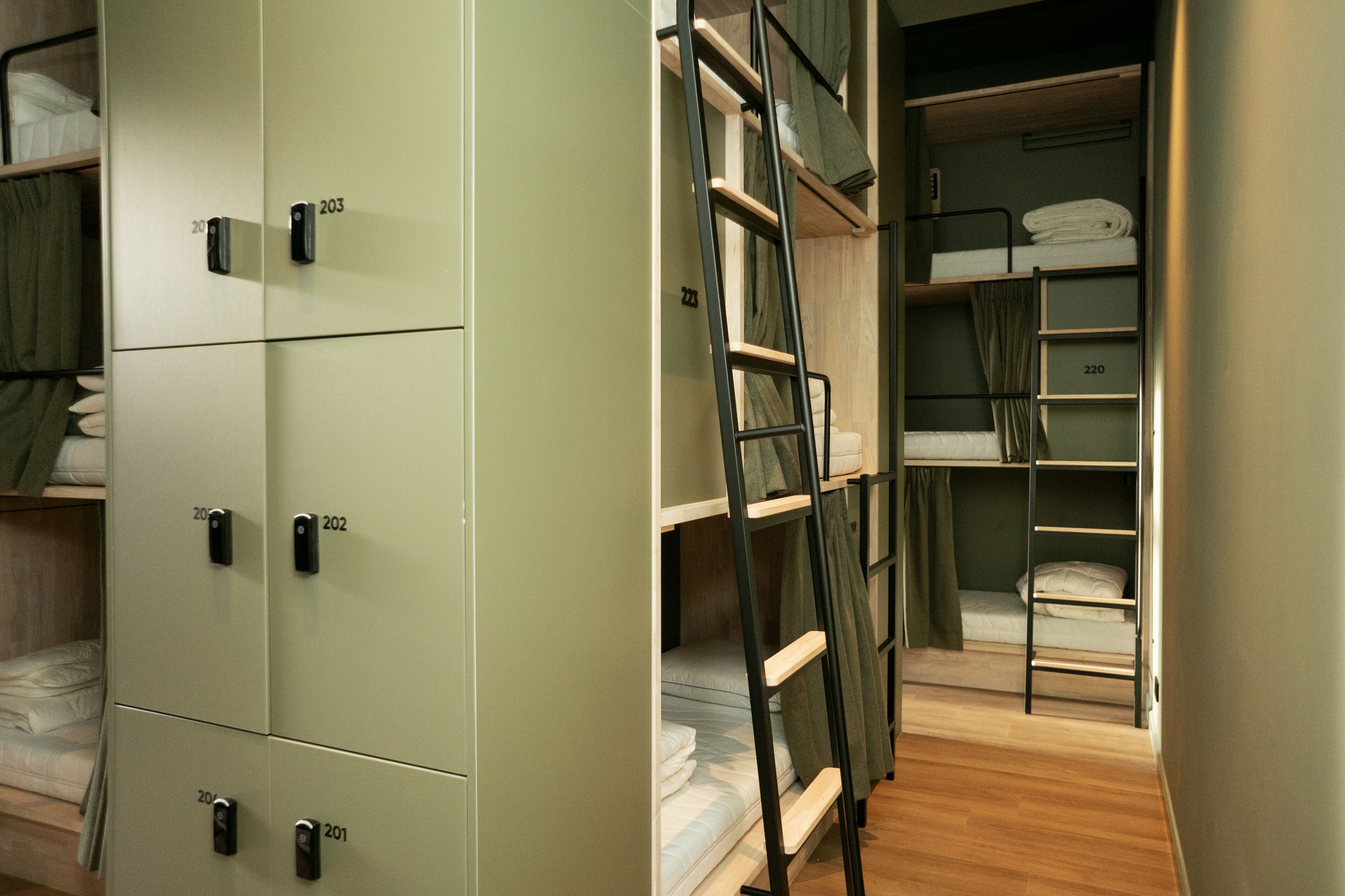 A compact hotel room with bunk beds, a wardrobe, and a ladder.
