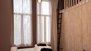 Una camera da letto con un letto, una finestra con tende leggere, una parete in legno e una scala.