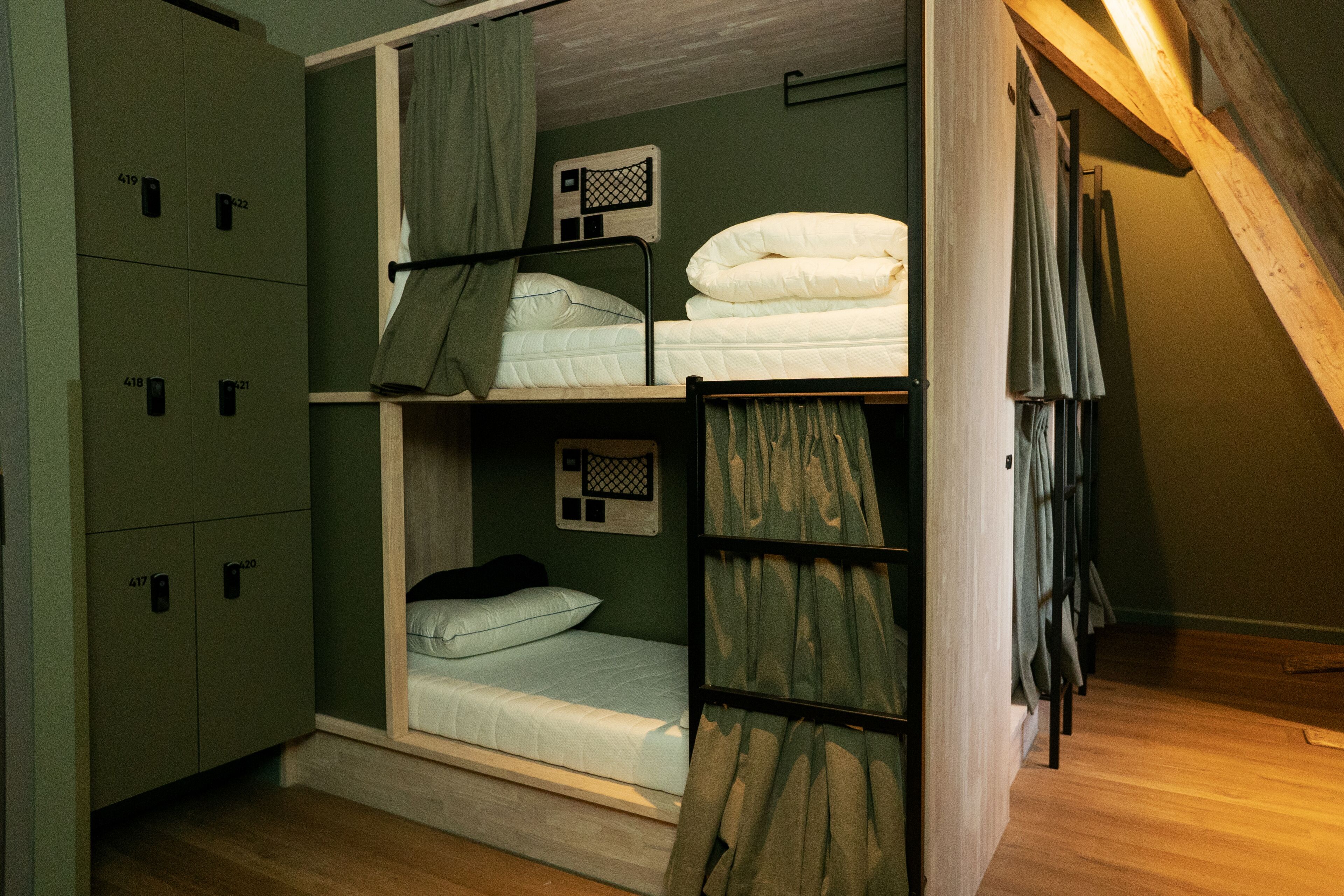 A dormitory-style room with bunk beds, a wardrobe, and a small window.