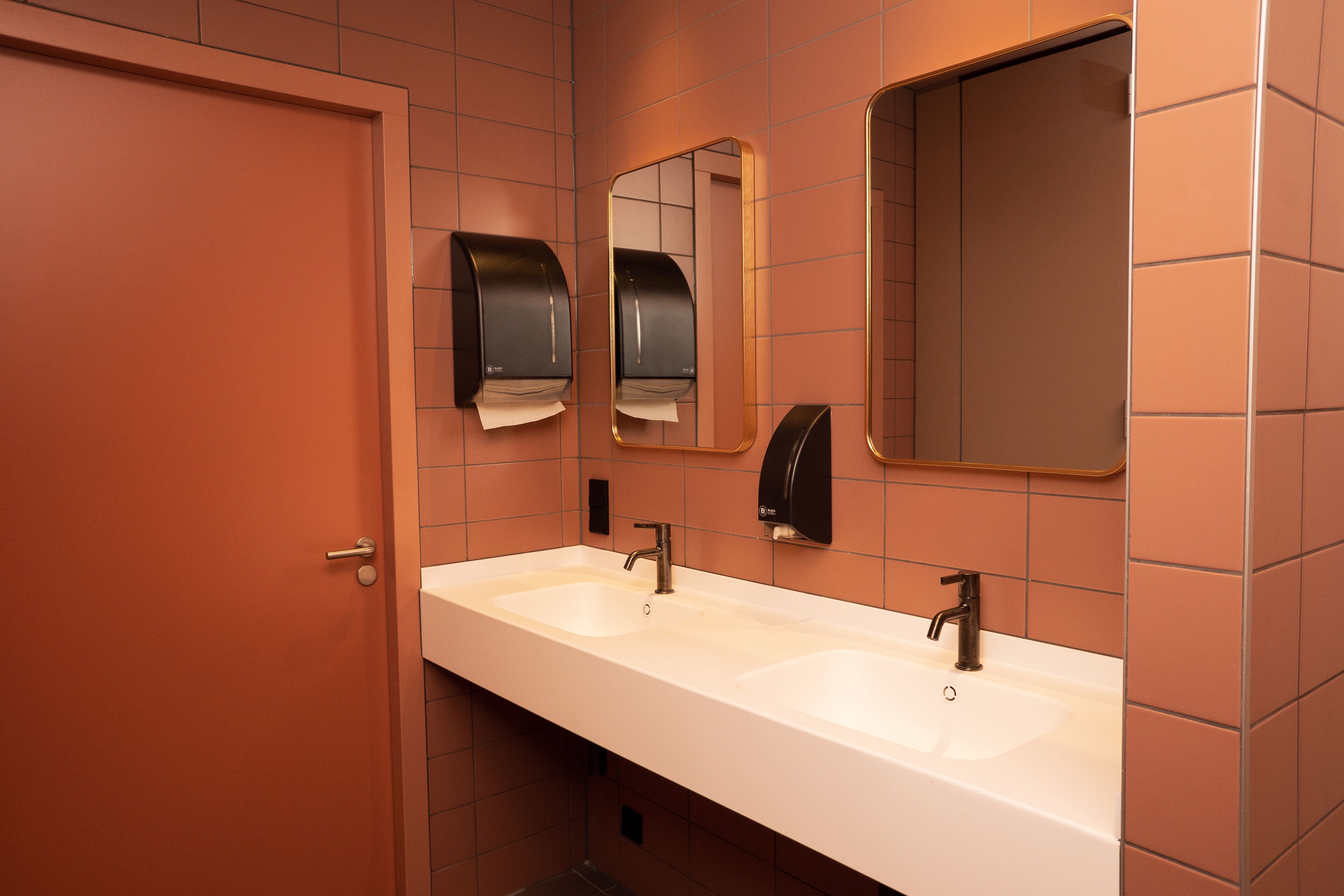 A bathroom with two sinks, a mirror, and a door.