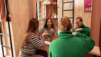 A room with a wooden wall, a mirror, and a shelf with folded clothes.