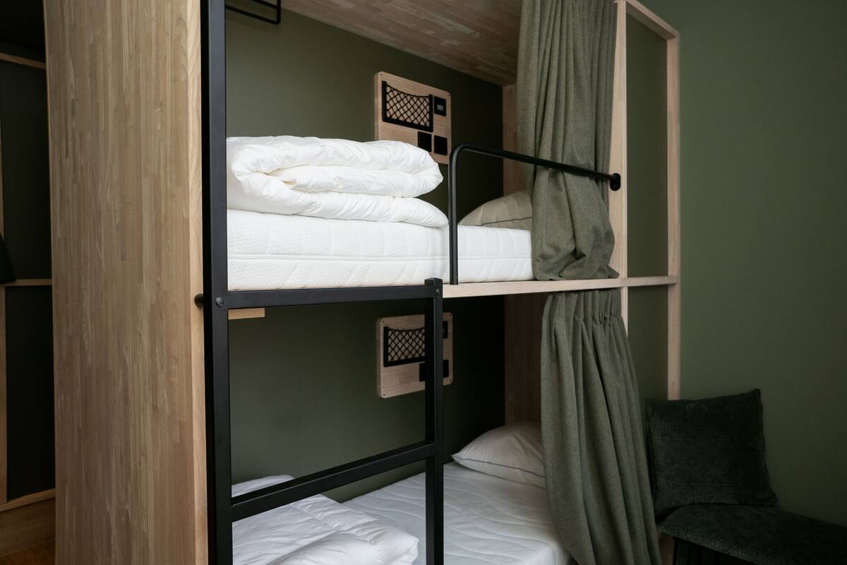 A bunk bed with a headboard and a chair in a room with green walls.