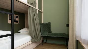 Un lit superposé avec une couverture verte, une chaise et un plancher en bois.