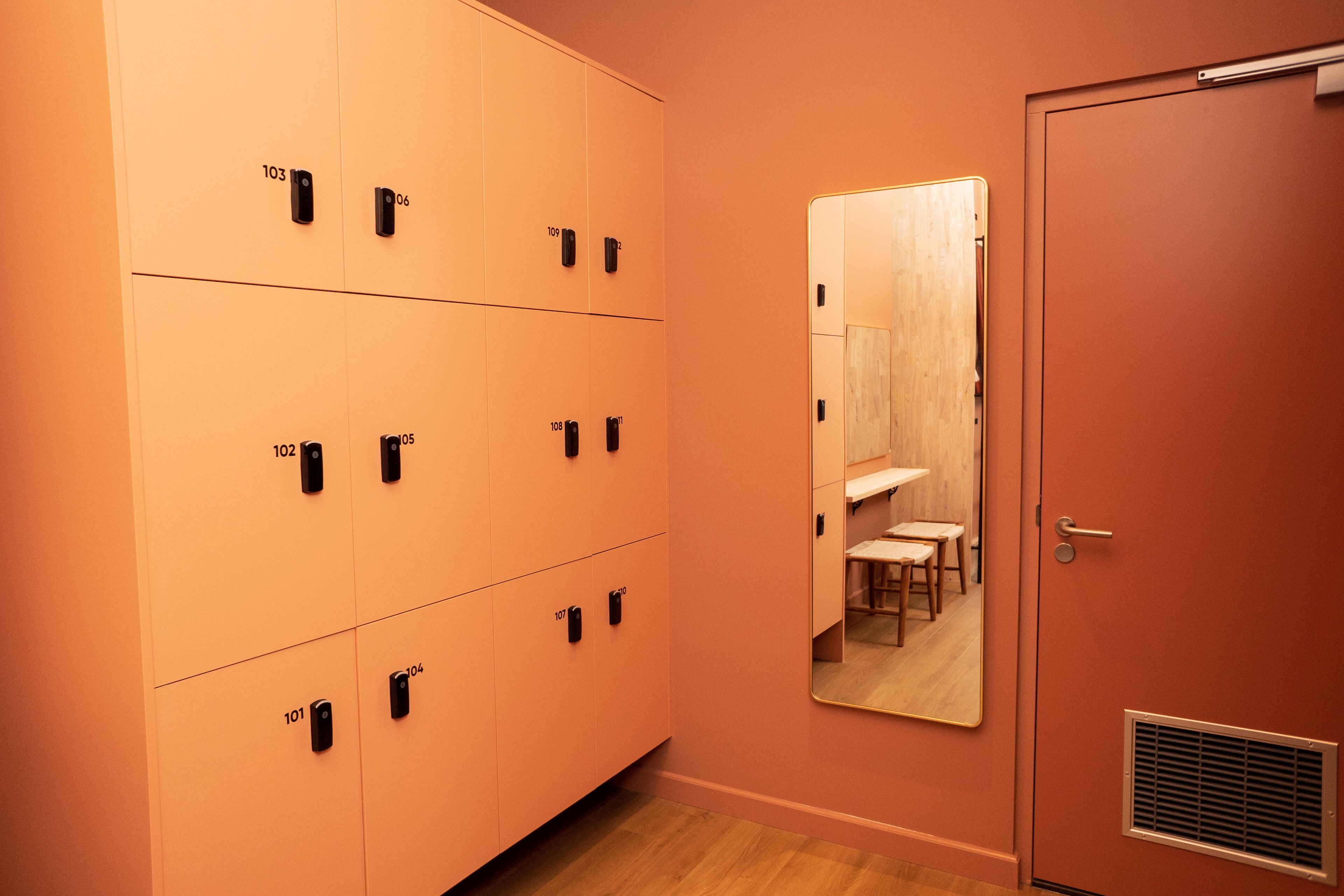 Ein Hotelzimmer mit einem großen Spiegel, Holzboden und einer Tür mit Lüftung.