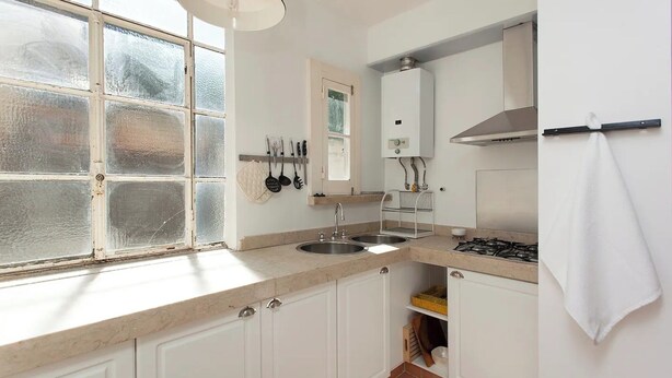 Cocina con ventana, pileta doble, estufa y gabinetes blancos.